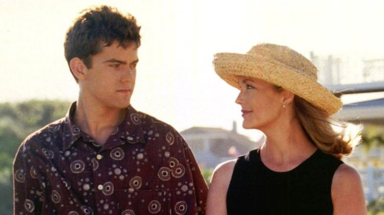 Pacey (Joshua Jackson) parece sério, enquanto Tamara (Leanne Hunley) o observa do lado de fora em Dawson's Creek, usando um chapéu de palha.