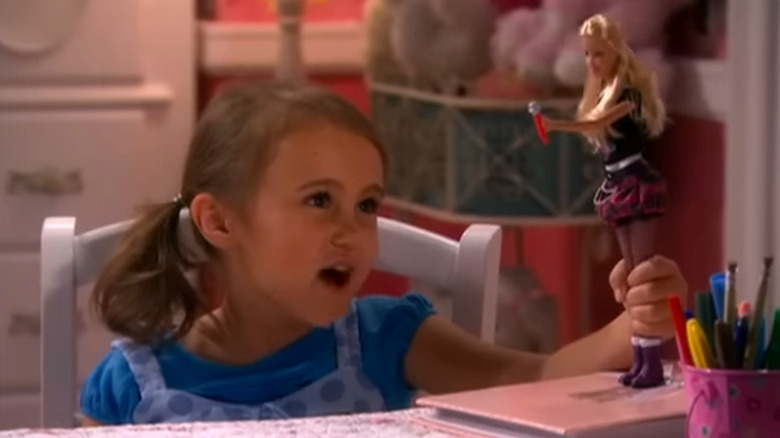 Little girl playing with doll in Hannah Montana