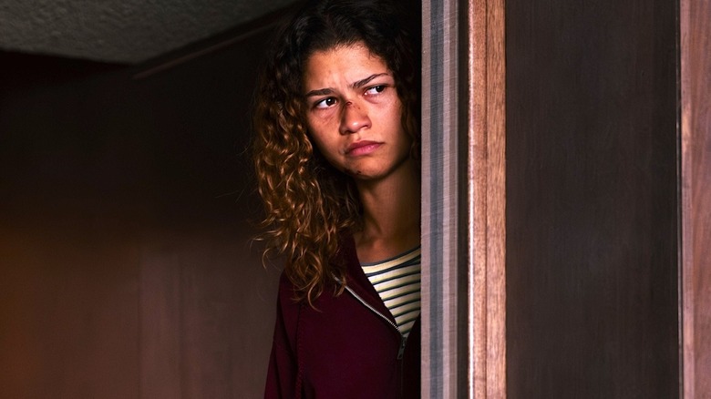 Rue peeking from behind a wall, looking scared