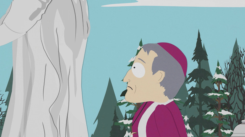 A priest stands beneath a statue of Mary on South Park