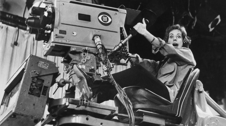 Carol Burnett looking excited while sitting in a hydraulic camera chair on the set of The Carol Burnett Show