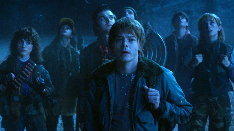 Jonathan Byers stands in front of a group including Nancy Wheeler, Dustin Henderson, Steve Harrington, Mike Wheeler, Will Byers, and Robin Buckley in "Stranger Things 5" (2025)