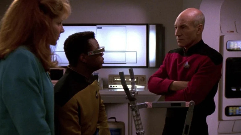 Beverly Crusher (Gates McFadden) and Geordi La Forge (LeVar Burton) speak to Jean-Luc Picard (Patrick Stewart) in Star Trek: The Next Generation