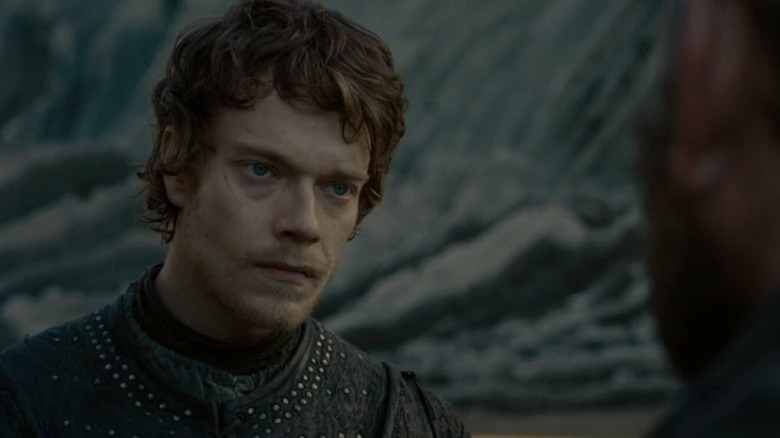Alfie Allen as Theon Greyjoy standing on a beach in Game of Thrones