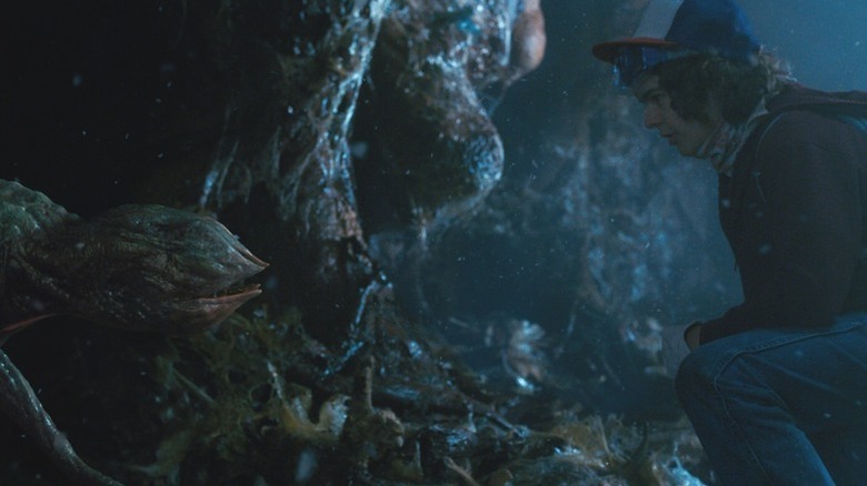 Dustin Henderson (Gaten Matarazzo) kneels before a Demo-Dog in Stranger Things