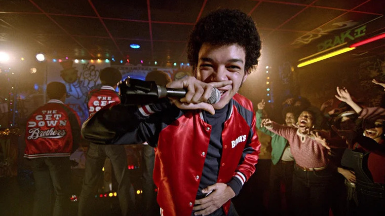 Justice Smith as Zeke in red jacket rapping into microphone in The Get Down