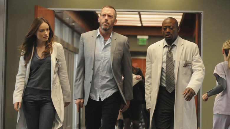 Remy "Thirteen" Hadley (Olivia Wild), Gregory House (Hugh Laurie), and Eric Foreman (Omar Epps) walking in a hallway in a publicity still for House Season 6, Episode 11
