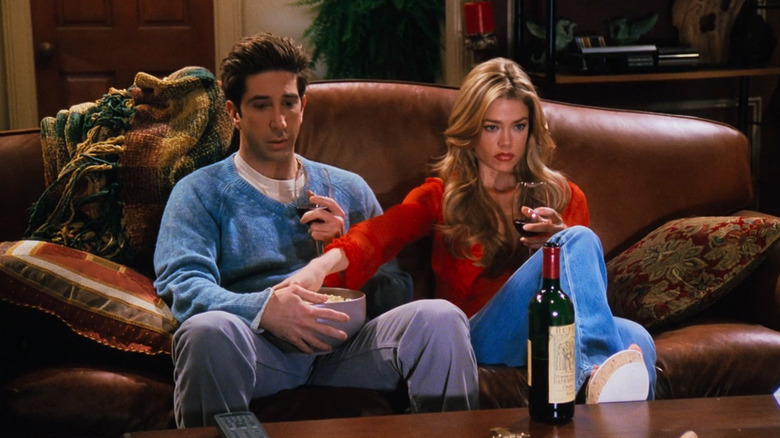 Cassie reaches into Ross's popcorn bowl