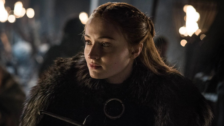 Sophie Turner as Sansa sitting outdoors in Game of Thrones