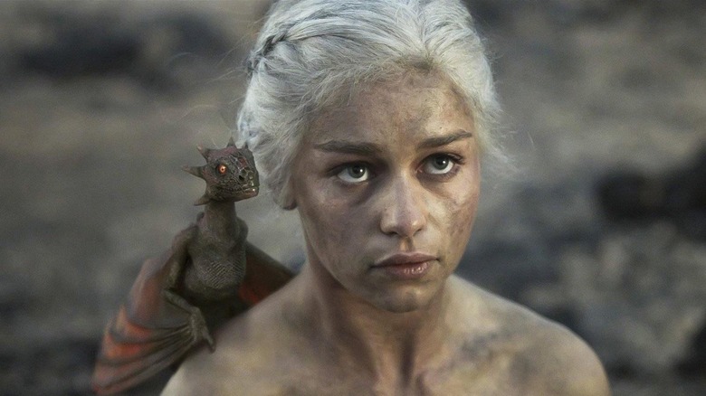 Emilia Clarke as Daenerys naked, covered in ash, and with a dragon on her shoulder in Game of Thrones