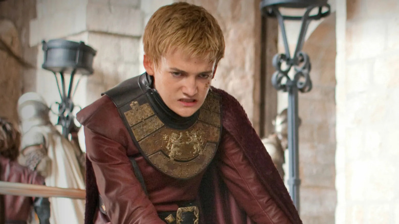 Jack Gleeson as King Joffrey sitting angrily in Game of Thrones