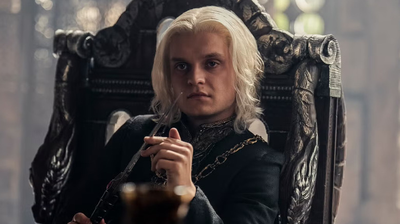 Tom Glynn-Carney as Aegon II playing with a knife on House of the Dragon