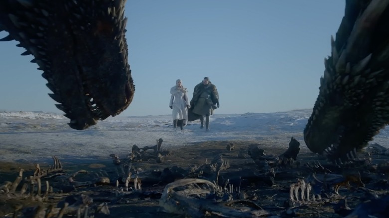 Emilia Clarke's Daenerys Targaryen and Kit Harington's Jon Snow approaching two large dragons on Game of Thrones