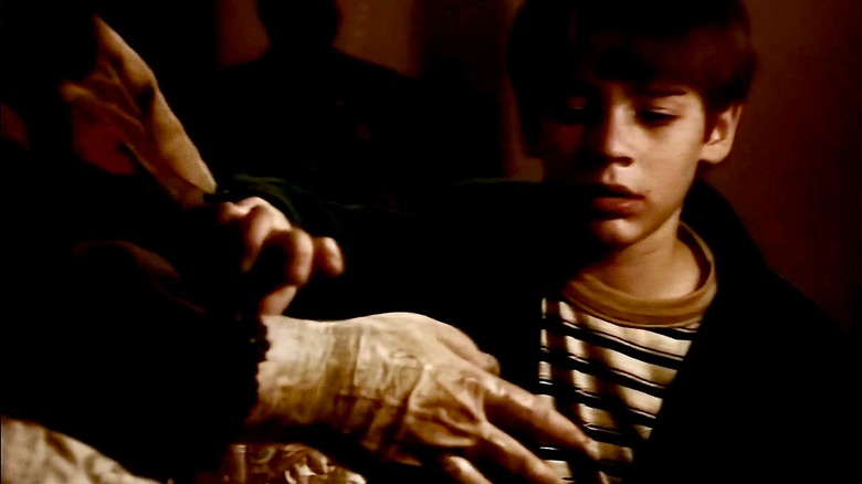 Georgie about to check his grandma's pulse by touching her hand