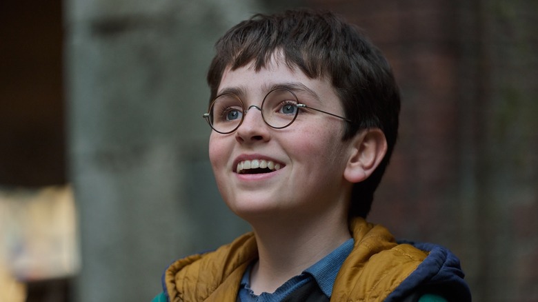 Dominic McLaughlin as Harry Potter smiling in a scene from the HBO series "Harry Potter and the Philosopher's Stone."