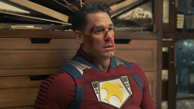 John Cena sits, stunned and bloodied as the Peacemaker.