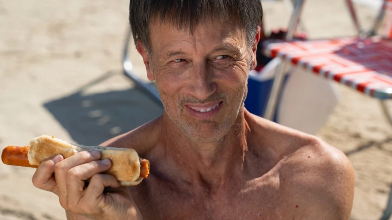 A man eats a hot dog on a Florida beach