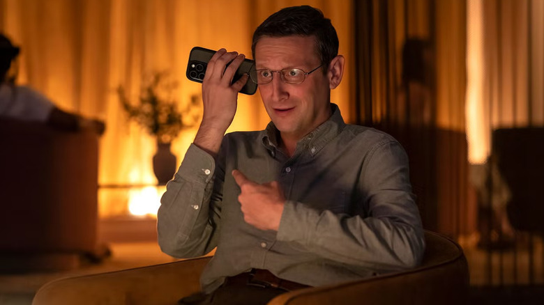 A Man listens to his cell phone's speaker.