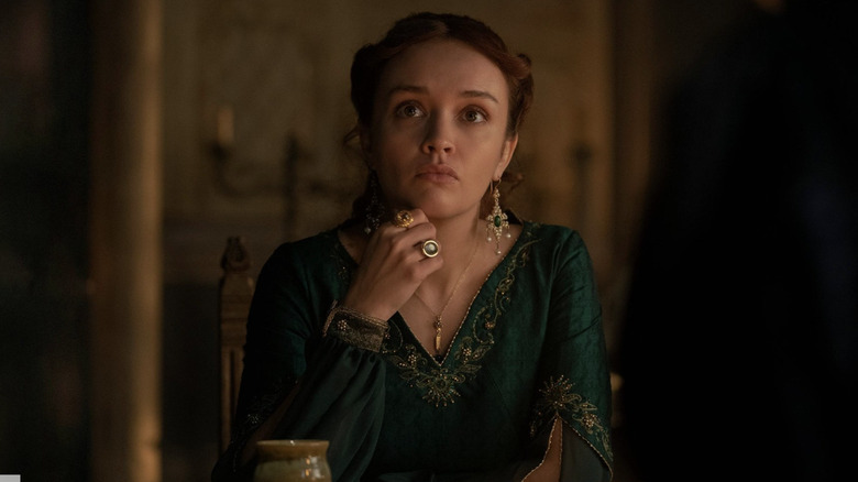 Olivia Cooke as Alicent Hightower sitting and thinking wearing a green dress and jewelery in House of the Dragon