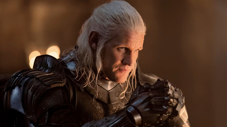 Matt Smith as Daemon Targaryen wearing armor with his hands together and hair tied back in House of the Dragon