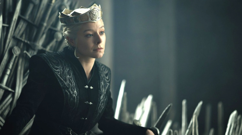Emma D'Arcy as Rhaenyra Targaryen sitting on the Iron Throne and wearing a crown in House of the Dragon