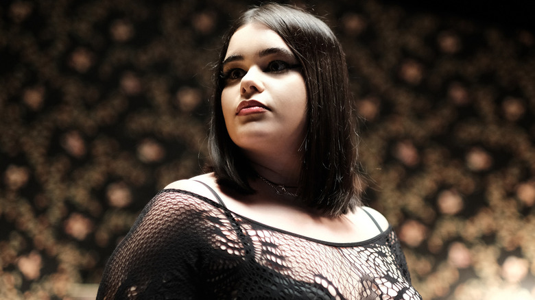 Kat wearing a black lace top striking a pose on stage