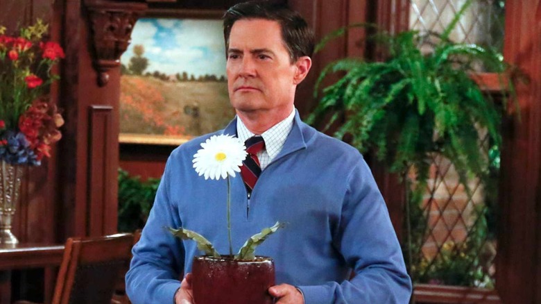 The Captain (Kyle MacLachlan) holding a daisy plant in "How I Met Your Mother" Season 9.