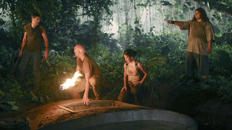 John Locke and Kate kneel on the Hatch while Hurley points a finger at Jack in the jungle on Lost (2004-2010)