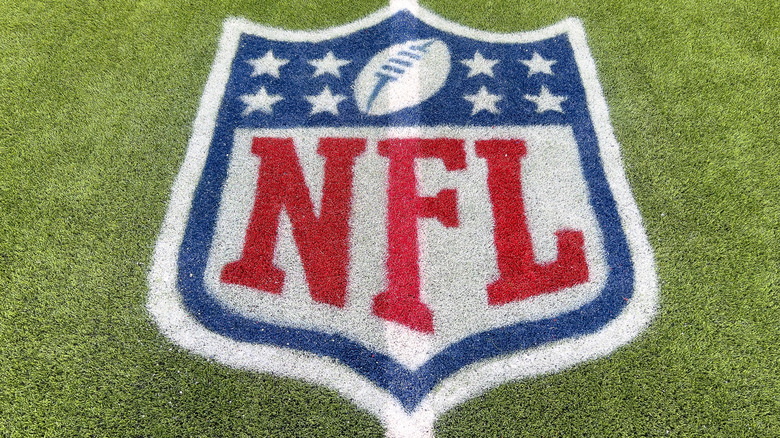 An NFL logo on the artificial grass of a football field.
