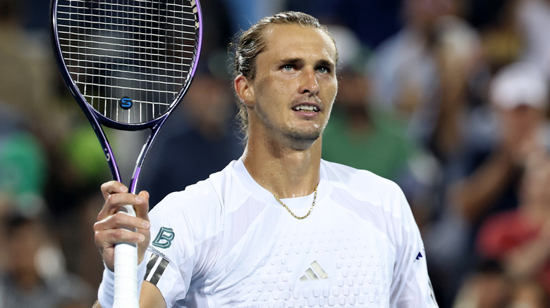 Alexander Zverev in a white shirt holding a tennis racket