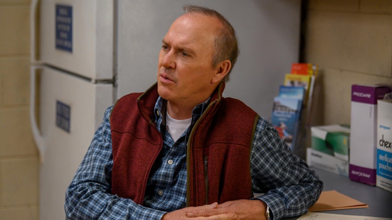 Samuel (Michael Keaton) in a vest sitting in a break room looking confused on Dopesick