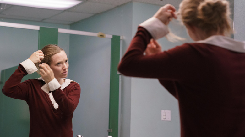 Elizabeth (Amanda Seyfried) fixing her hair in a bathroom mirror on The Dropout