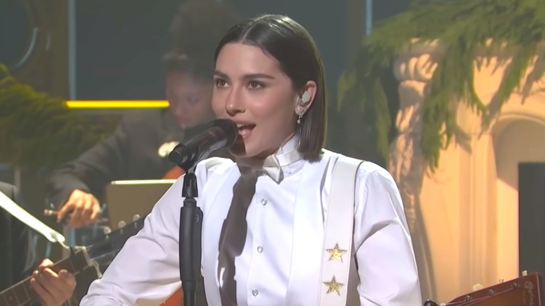 Gracie Abrams holding a guitar and singing into a microphone on "Saturday Night Live."