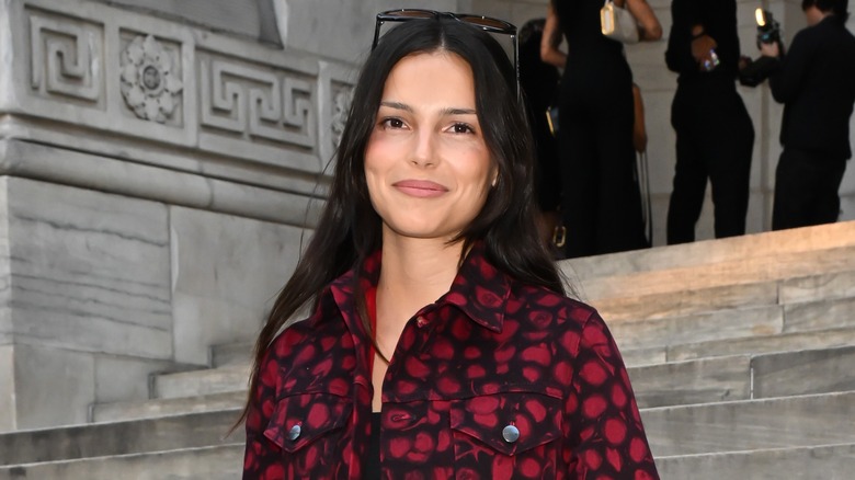 Inde Navarette wears a red and black shirt while standing on a staircase.