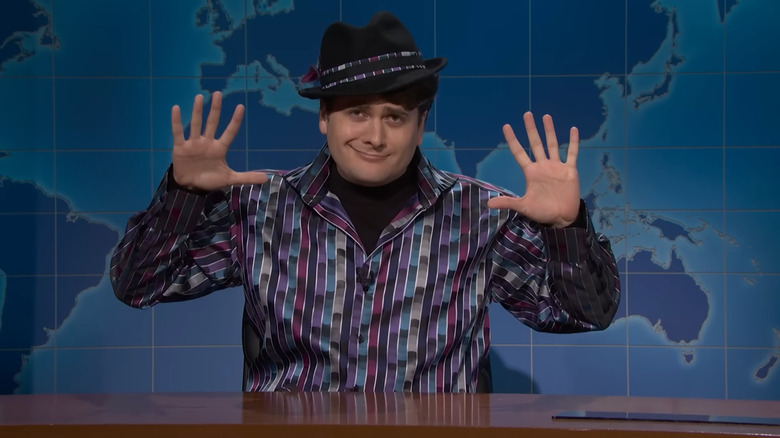 Jeremy Culhane raising his hands and wearing a fedora on Saturday Night Live