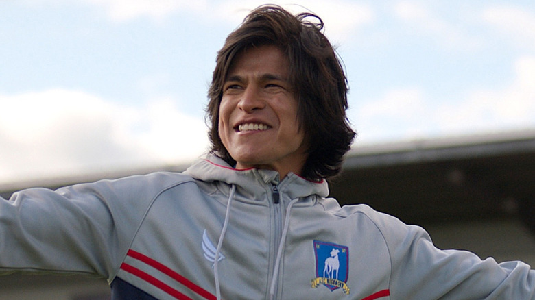 Dani Rojas in a gray AFC Richmond jacket with his arms out wide in 