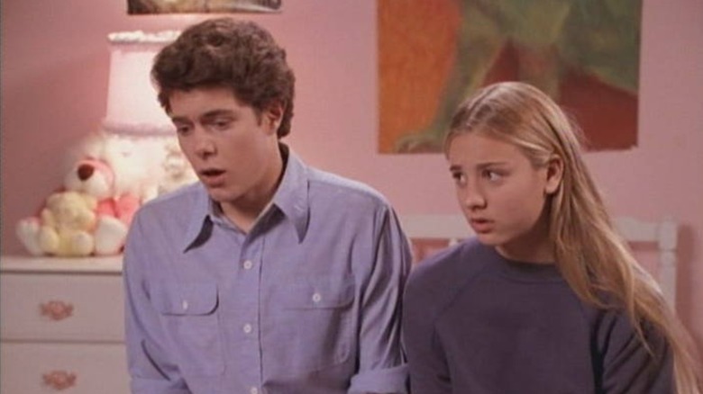 Adam Brody as Barry Williams and Kaley Cuoco as Maureen McCormick sitting on bed in bedroom set in "Growing Up Brady"
