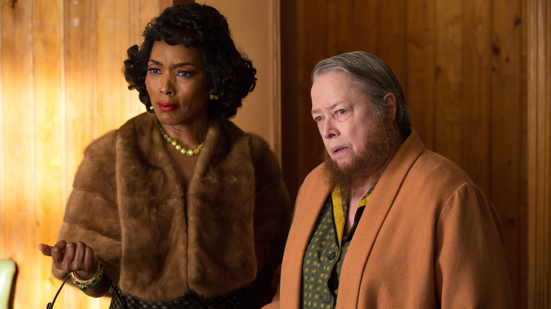 Desiree Dupree (Angela Bassett) in a fur jacket and pearls, and Ethel Darling (Kathy Bates) in a tan coat and green button-down, both wearing expressions of disbelief in American Horror Story: Freak Show