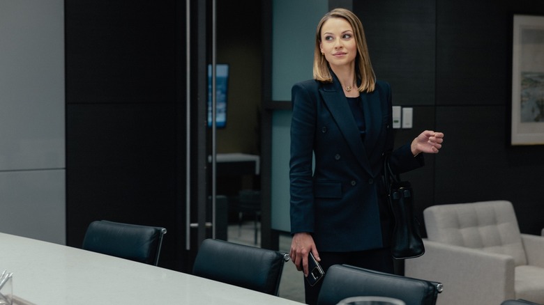 Kayla Wallace as Rebecca stands near a conference table looking smug on Landman