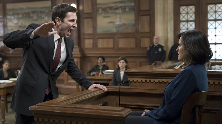 William Lewis in a suit yelling as a seated Olivia Benson with his hand raised in a courtroom in Law and Order: SVU