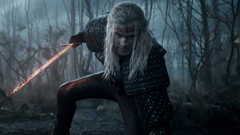 LIam Hemsworth's Geralt of Rivia holding a glowing sword on The Witcher