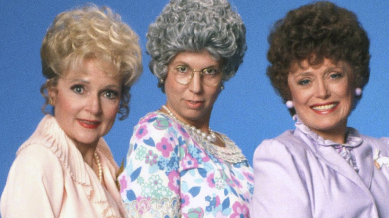 Ellen Harper-Jackson (Betty White), Thelma "Mama" Harper (Vicki Lawrence), and Fran Crowley (Rue McClanahan) pose together, lifting their skirts to reveal their legs against a blue studio backdrop