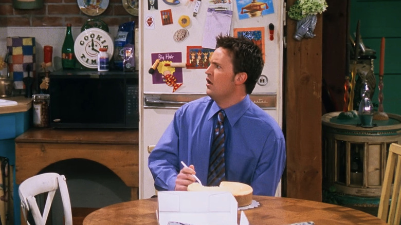 Chandler Bing sits at the kitchen table looking surprised in "Friends" (1994-2004)