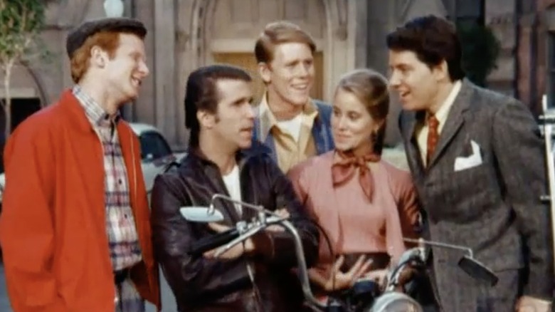 Ralph, Richie, Hildie, and Potsie gathered around Fonzie on motorcycle