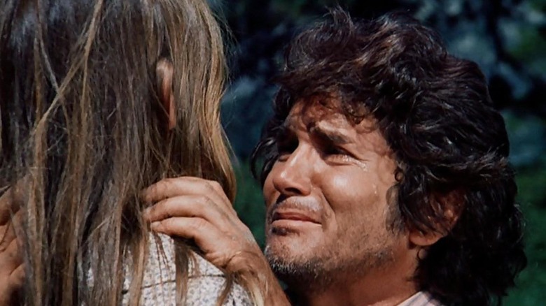 Charles Ingalls crying while kneeling in front of Laura and holding her shoulder