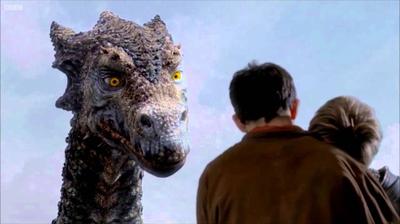 Merlin (Colin Morgan) holds a woman as he heeds the words of the great dragon, Kilgharrah (John Hurt) on "Merlin."