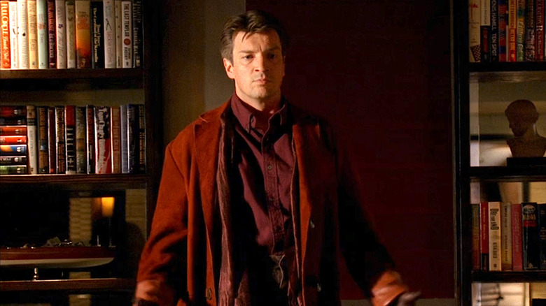 Nathan Fillion as Richard Castle in the "Firefly" outfit standing in front of a bookshelf