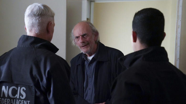 Christopher Lloyd standing in front of Mark Harmon as Gibbs and Wilmer Valderrama as Torres in NCIS