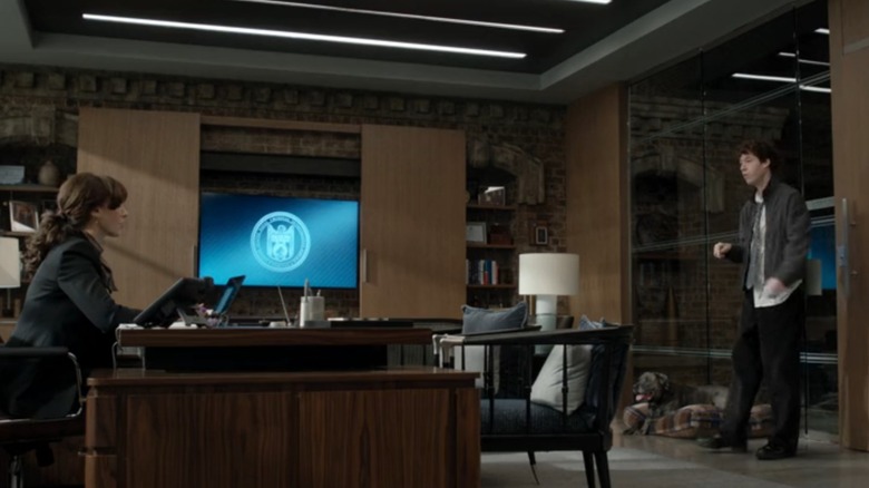 Jennifer Beals as Robyn Wells and Devin Druid as Sean Sullivan in Wells' office with a dog resting by the door on "NCIS: New York"