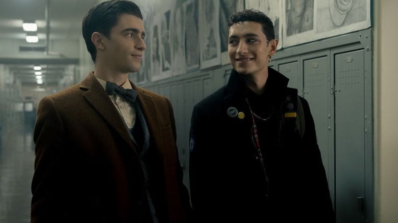 Edwin Payne and Charles Rowland smirk at each other in a hallway.